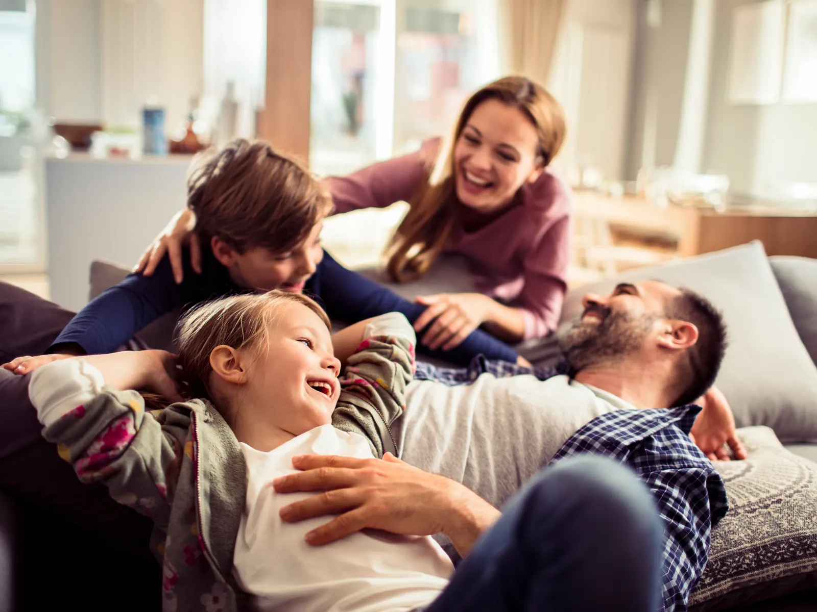 Familie mit zwei Kindern zu Hause auf dem Sofa – gemeinsame Veranlagung für Ehepaare und Familien
